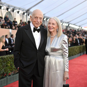 Alan Arkin and Suzanne Newlander Arkin at the Screen Actors Guild Awards. Alan in a black tuxedo. Suzanne in a long, elegant silver gown. Onstage with a large audience.