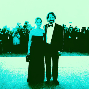 Anne Heche and Coley Laffoon at the premiere. Anne in a chic black evening gown. Coley in a tuxedo. They pose together with a warm smile. Crowd and flashing cameras in background.