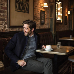 Jake Gyllenhaal, dressed in a smart casual outfit, hanging out in a trendy cafe. The cafe has brick walls and vintage decor.