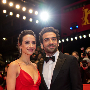 Elyas M'Barek and Jessica M'Barek at the Berlinale premiere. Formal attire, bright lights, crowd in background