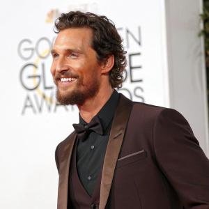 Matthew McConaughey, at Golden Globe Awards, standing confidently. White background, sharp suit, smiling