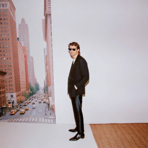 Garrett Hedlund at the premiere of his new film. Dressed in a sleek black suit and dark shades. He stands confidently in front of a bustling city backdrop.