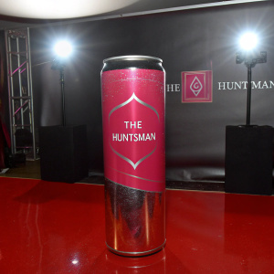 A sleek can with the logo of 'The Huntsman' standing out on a glossy black backdrop. The can's metallic surface gleams under studio lights.