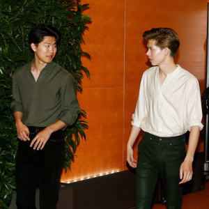 Lee Ki-Hong and Thomas Sangster at the Cannes Film Festival press conference. Lee in gray shirt, Thomas in white shirt. Red carpet backdrop.
