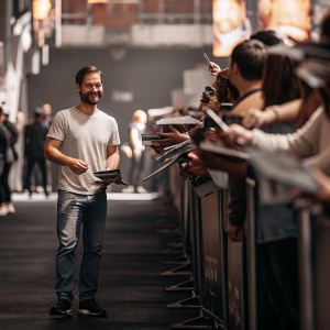 Tobey Maguire in a casual meet-and-greet session, surrounded by fans at a Comic-Con event.
