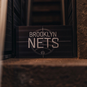 A sleek, modern logo design for the Brooklyn Nets. The emblem features interlocking circles and bold typography on a vibrant blue backdrop.