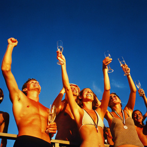 Adam Peaty, Chris Walker-Hebborn, Siobhan-Marie O'Connor, and Fran Halsall, celebrating victory in a swimming gala. Champaign glasses raised in the air, vibrant cheers in the background