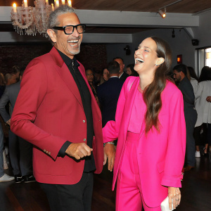Jeff Goldblum and Emilie Livingston laughing together. Crowded party with chandeliers