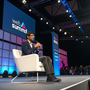 Rohit Prasad, Amazon's Alexa Head Scientist, speaking at Web Summit. He is seated on a white chair on the main stage.