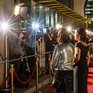 Meg Tilly and Jennifer Tilly at a glitzy awards ceremony. Meg in a shiny silver top, Jennifer in a sleek black dress. Crowded red carpet scene.