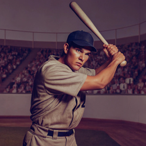 Luis Urias, baseball player, in intense batting stance. Gray jersey number 2, wearing dark blue cap. Stadium crowd blurred, highlighting action.