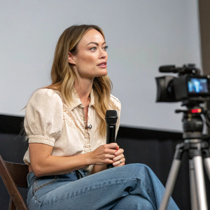 Olivia Wilde at the virtual press conference, wearing a casual blouse and jeans.