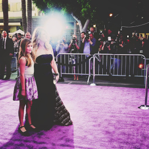 Kirstie Alley and her daughter Lillie Price at a Hollywood movie premiere. A crowd of fans and paparazzi gather around them. Black carpet event with flashing cameras.