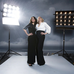Actresses Annie Parisse and Kate McKinnon at the Elle Awards. Both are dressed in black and white outfits.