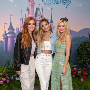 Remy Thorne, Pia Mia, and Bella Thorne at a charity gala. Disney-themed backdrop with greenery in the background. Casual outfits.