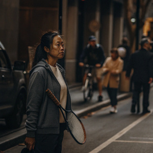 Anne Keothavong, asian female tennis player, on a busy city street. She's dressed in casual adidas gear. Focused look