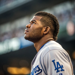 Yasiel Puig, baseball star, intense focus. Wearing Dodger's jersey. Stadium background blurred, highlighting his determination.