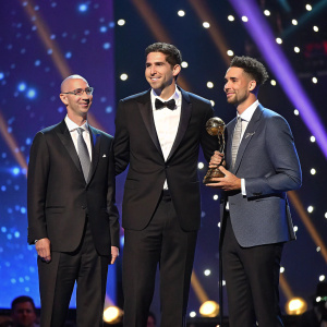 Adam Silver, Bob Myers, and Klay Thompson at a glamorous NBA awards ceremony. Spectacular light show in the background