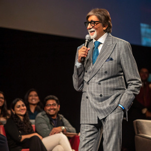 Amitabh Bachchan, in a gray pinstriped suit and blue tie, during a lively Q&A session at the Toronto International Film Festival.