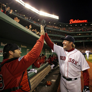 Curt Schilling and Jason Varitek in the dugout, celebrating a win. Baseball stadium with cheering fans in the background.