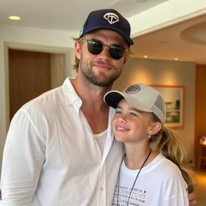 Chris Hemsworth and India Rose Hemsworth posing indoors. Dad in white shirt, sunglasses, cap. Daughter in cap, t-shirt, ponytail. Family photo