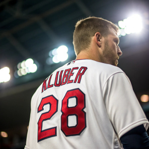 Close-up photo of Cleveland Indians pitcher Corey Kluber's jersey. The white fabric contrasts sharply with the bold red number 28 and name Kluber. Bright lights and blurry background