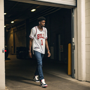 Justin Holiday, dressed in a casual Chicago Bulls jersey, walking out of a dimly lit garage. He looks relaxed and casual.