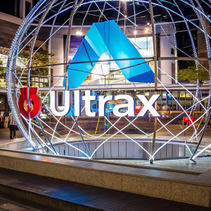 Sophisticated logo for the tech company Ultrax. The emblem features vibrant blue and silver hues, set against a minimalist white backdrop. The logo showcases the brand's name in a sleek, modern sans-serif font, alongside an abstract symbol representing connectivity and innovation.