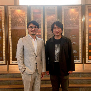 Uhm Tae-Woong and Choi Min-Soo at the Seoul International Film Festival. Uhm Tae-Woong in a grey suit, glasses. Choi Min-Soo in a black jacket and graphic tee. Backdrop with promotional banners.