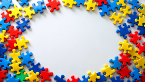 Blue, yellow, red pieces of puzzle frame on white background. World autism awareness day concept. Top view, copy space