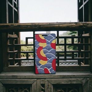 Photograph of Meitu M8 phone packaging. Modern design inspired by ancient Chinese architecture. Eye-catching blue cover with vibrant red, yellow, and white abstract shapes. Traditional and modern elements merge. Dramatic and unique.