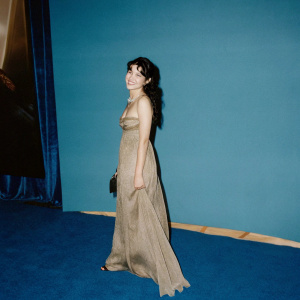 Valerie Perez at the world premiere of Wonder Woman. Cheerful face, long flowing gown. Movie backdrop, red carpet area.
