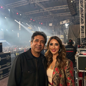 Carlos Marín and Kim Sharma at the bustling backstage area. Event crowd and sound equipment visible.