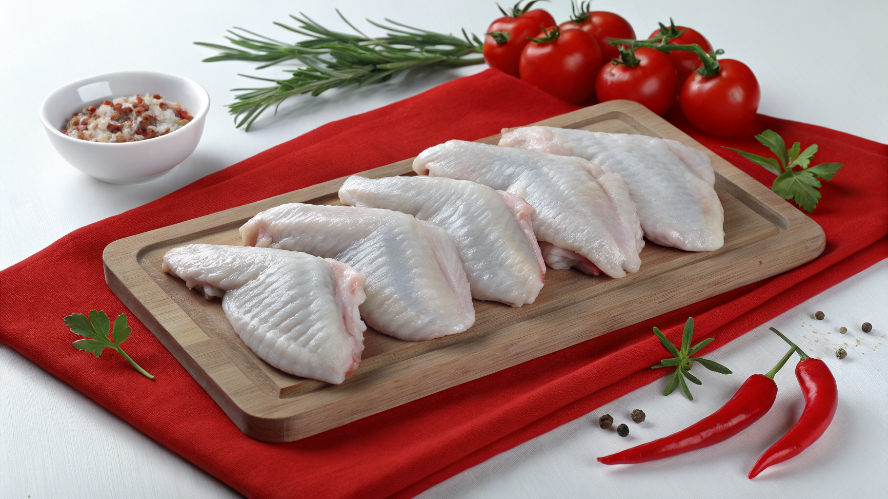 Fresh raw chicken wings laid out on a butcher's wooden board