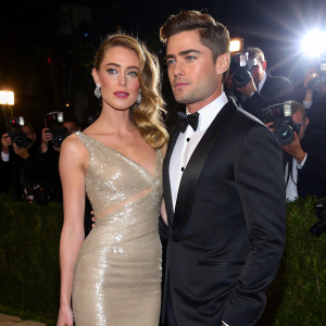 Amber Heard and Zac Efron at the glamorous Oscars party. She wears a stunning silver gown, he in a black tuxedo. Paparazzi flashing cameras