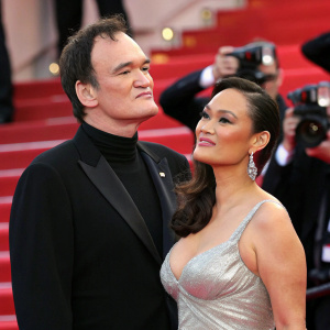 Quentin Tarantino, in black turtleneck, and Tia Carrere, wearing a shimmering silver dress, at Cannes Film Festival premiere.