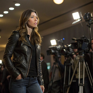 Jessica Biel, dressed in a black leather jacket and jeans, looking intense at a press conference.
