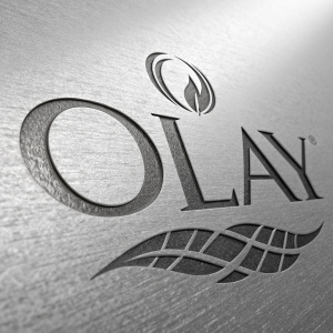 Olay logo in a sleek, metallic texture advertisement. Monochromatic color palette, reflective background, high-end product presentation.