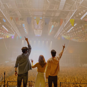 Diego Dominguez, Martina Stoessel, and Jorge Blanco at a vibrant concert venue. The crowd is cheering wildly.