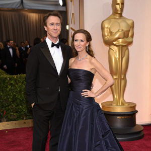 Ed Norton and Shauna Robertson at the Met Gala. Wearing elegant black tuxedo and strapless gown with long train. Golden Oscar statue on display.