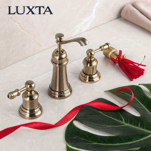 Advertisement for Luxta brand kitchen and bathroom fixtures. Sleek, modern design with emphasis on quality and aesthetics. Brand logo at top. Dark green leaf in foreground. High-quality photograph with metallic finishes and natural elements. Red ribbons点缀。整体色调柔和现代，强调金属质感和自然元素。