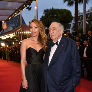 Laura Smet and Claude Chabrol at Cannes Film Festival. She wears a black gown, he a navy suit. Crowd in background. Festive atmosphere.