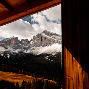 An awe-inspiring panorama of the Dolomites Alps, South Tyrol, Italy. Snow-capped peaks towering over lush green valleys, set against a backdrop of a vivid blue sky dotted with soft, puffy clouds.