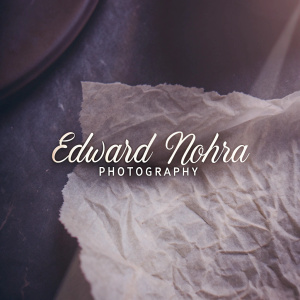 Edward Nohra Photography logo. Elegant and sophisticated design with gold cursive text on a dark background. Rough texture adds uniqueness.