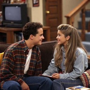 A snapshot from Boy Meets World, Cory Matthews and Topanga Lawrence sitting on the couch, engaged in a friendly conversation.