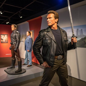Arnold Schwarzenegger wax figure display at Madame Tussauds Berlin. Various poses and outfits, including a classic movie hero stance with a sword.