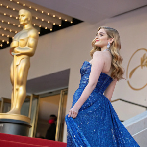 Willow Shields at Cannes Film Festival. Wearing a blue sequined dress. Golden statue backdrop.