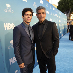 Elvimar Silva and Esai Morales at the premiere event. Dressed in formal attire. Brightly lit blue carpet with HBO logos backdrop.