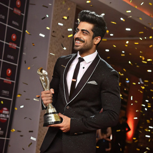 Gautam Gulati, celebrated actor, poses with a gleaming trophy at the prestigious awards night. Formal black suit with a matching tie, amidst a flurry of confetti.