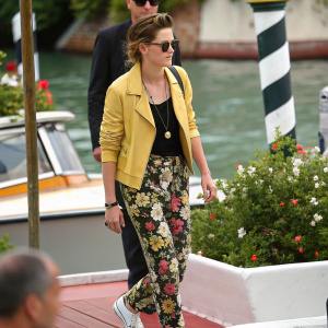 Kristen Stewart, casual attire, floral patterned pants, yellow jacket, black top. Candid shot at the Venice Film Festival.